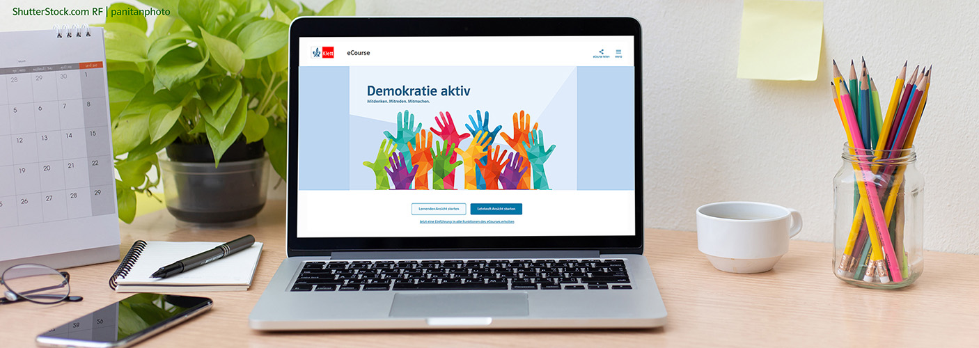 Schreibtisch mit Schreibutensilien und einem Laptop, auf dem der eCourse Demokratie aktiv zu sehen ist